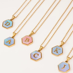 Close-up of hexagonal 18K gold plated pendants with colorful shell inlay and initial letters