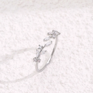 Leaf design open ring with micro-pave zircons on a textured white surface