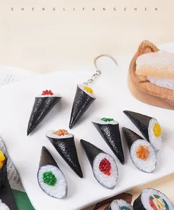 Detailed view of realistic sushi hand roll keychains with salmon and roe on a ceramic plate