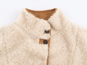 Detail of sherpa fleece jacket with high collar, brown suede accents and button closure