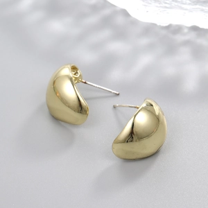 Macro shot of minimalist gold teardrop stud earrings with a high-polished mirror finish