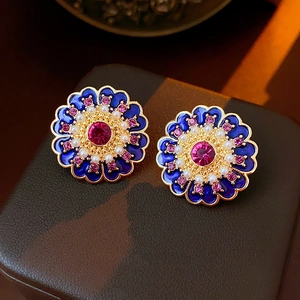 Macro view of blue enamel flower earrings with magenta crystals and pearls on jewelry box