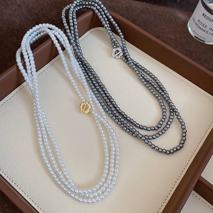 Detail of multi-layered pearl necklace with golden flower clasp on premium leather tray