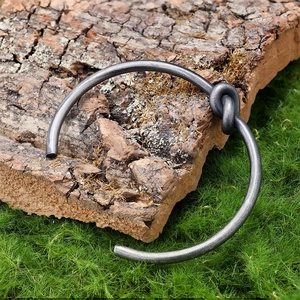 Close-up of vintage steel knot open cuff bracelet on natural moss and bark background