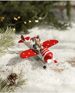 Detailed view of metal reindeer flying red airplane ornament in a festive snow scene