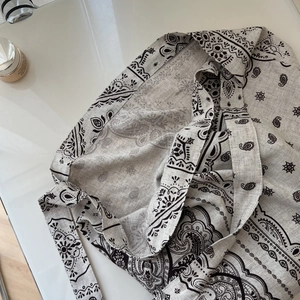 Detailed texture of beige linen tote bag with classic black paisley pattern print