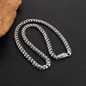 Titanium steel silver Cuban link necklace with rectangular clasp on dark textured background