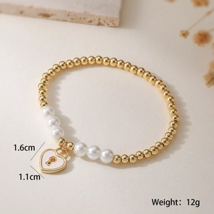 Detailed view of heart pendant 1.6x1.1cm on gold beads and white pearl bracelet