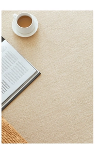 Detail of beige textured rug fabric with coffee cup and book for a cozy home feel