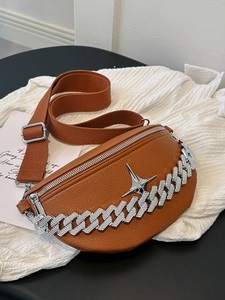 Detailed macro of brown lychee leather cross-body bag with silver chain and star charm