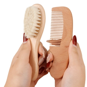 Natural wood baby hair brush and wide-tooth comb set held against white background