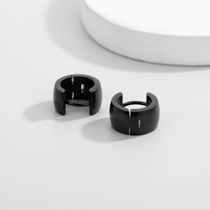 Detail of black wide-band hoop earrings with high-gloss finish and hinged closure