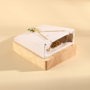 Solid wood necklace display stand with beige velvet pad and green gemstone pendant