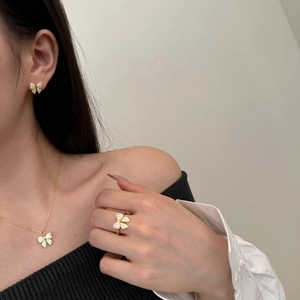 Close-up of golden bow jewelry set with clear zircons worn by a model in soft light