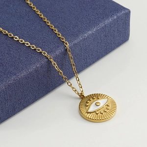 Macro detail of gold-plated evil eye pendant on stainless steel chain with blue box