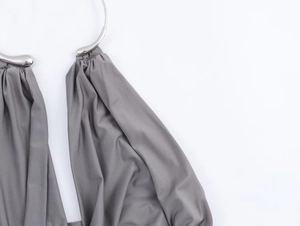 Close-up of grey fabric with silver metal ring buckle detail on the dress halter neckline