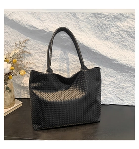 Detail shot of the black woven leather texture and large capacity design of the tote bag