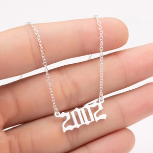 Close-up of gothic silver year 2002 pendant on a fine stainless steel chain
