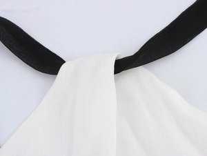 Détail du tissu blanc texturé avec bretelles licou noires contrastées sur la robe