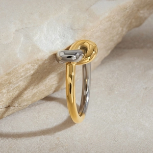 Detail of two-tone gold and silver knot ring on stone with soft lighting effects