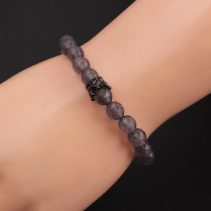 Macro detail of 8mm faceted stone beads and black crown charm on a mens beaded bracelet