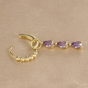 Detail of golden huggie hoop earring with three purple pear-cut zircon stones