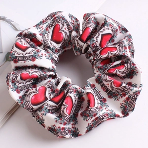 Detail showing white satin hair scrunchie with red heart patterns and Love text