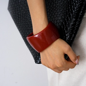 Close-up of a wide chunky red resin bracelet with a high-gloss finish on a woman wrist