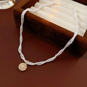 Detail of double-layer pearl necklace with gold starburst pendant on jewelry box