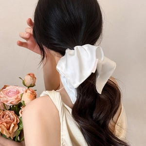 Detailed back view of a white oversized satin bow scrunchie on long hair hairstyle