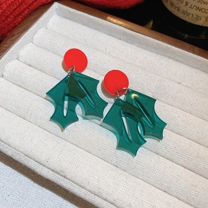 Close-up of Christmas tree holly leaf earrings in festive red and green colors