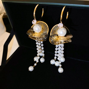 Close-up of golden tassel earrings with white pearls and sparkling cubic zirconia details