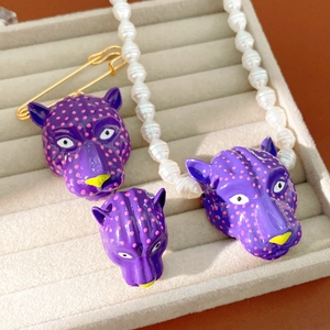 Vue détaillée d'un ensemble de bijoux tête de léopard violet avec des perles blanches