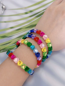 Primer plano de pulseras elásticas de cristal de corazón macaron coloridas en la muñeca de modelo.