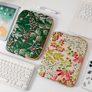 Detail of embroidered floral iPad cases in green and pink colors on white desk