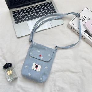 Detailoverzicht van lichtblauw denim telefoonhoesje met sterrenprint en rode knop