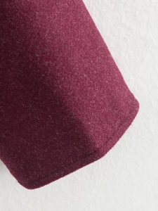 Detailed close-up of wine red wool jacket fabric with premium stitching on the cuff edge