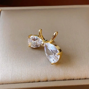 Gros plan d'une broche nœud dorée avec zircons poire sur fond de couleur champagne