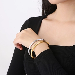 Close-up of gold and silver Mobius bangle bracelets showing mirror polished metal finish