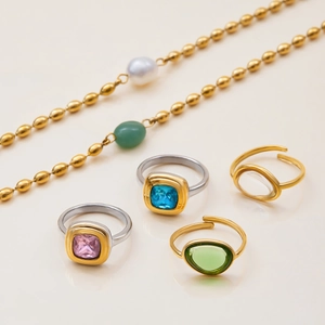 Variedad de anillos con piedras preciosas y joyería dorada con perlas en beige