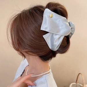 Detailed view of grey satin fabric bow hair claw with Believe In Yourself engraving