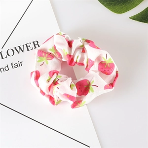 Close-up of a white scrunchie with pink strawberry prints on soft chiffon fabric
