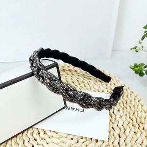 Détail d'un serre-tête tressé de luxe avec strass gris foncé sur boîte minimale