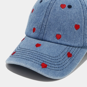 Détail macro de broderie cœur rouge sur la surface en denim bleu de la casquette