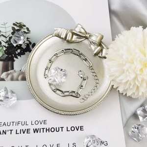 Detailed view of silver paperclip chain bracelet with lobster clasp on decorative tray