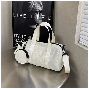 Detail showing white nylon cylinder bag texture with round coin purse and broad strap