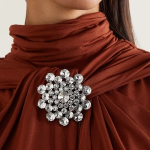 Elegant silver round crystal floral brooch with sparkling rhinestones worn on a suit
