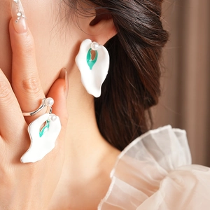Detailed view of silver enamel flower earrings and ring set with elegant pearls