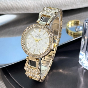 Détail d'une montre dorée élégante pour femme avec lunette en strass et cadran argenté texturé