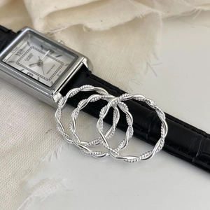 Close-up of three 925 sterling silver twisted rope rings on a white textured surface